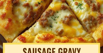 Golden sausage gravy breakfast pizza topped with melted cheese and savory sausage crumbles on a flaky crust.